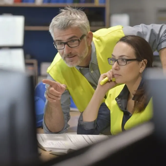 Two people looking at a computer screen - One is pointing at the screen