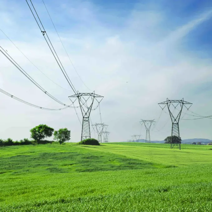 Power Transmission and Distribution - Pylons with green grass and blue sky